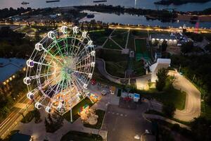 schön Sonnenuntergang Über das Stadt mit ein beleuchtet Ferris Rad. foto