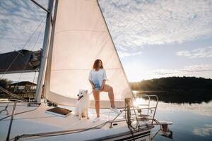 ein glücklich Frau mit ein groß Weiß Hund auf ein Weiß Yacht im das Meer foto