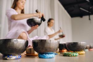 zwei weiblich Yoga Lehrer abspielen auf tibetanisch Schalen im das Fitnessstudio während ein Yoga Rückzug foto