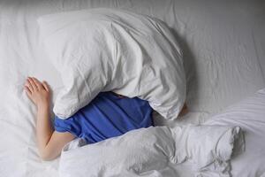 Frau Schlafen im Bett mit Kissen Über ihr Kopf foto