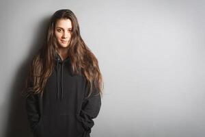 jung Frau tragen schwarz Sweatshirt gelehnt gegen grau Mauer mit Kopieren Raum foto