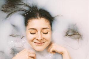glücklich jung Frau nehmen ein Bad im Milch foto