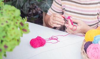 Nahansicht von Frau Hand Stricken mit Rosa wolle foto