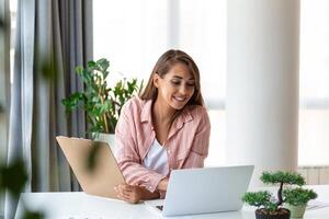 Remote-Job-, Technologie- und People-Konzept - glücklich lächelnde junge Geschäftsfrau mit Laptop-Computer und Papieren, die im Home Office arbeiten foto
