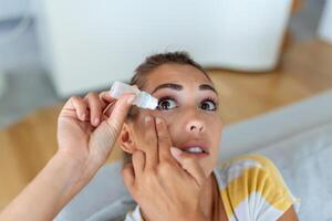 Frau mit Auge tropfen, Frau fallen lassen Auge Schmiermittel zu behandeln trocken Auge oder Allergie, krank Frau Behandlung Augapfel Reizung oder Entzündung Frau Leiden von gereizt Auge, optisch Symptome foto