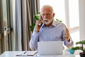 reifen Geschäftsmann Arbeiten auf Laptop und reden auf Handy. gut aussehend reifen Geschäft Führer Sitzung im ein modern Büro foto