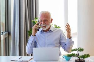 reifen Geschäftsmann Arbeiten auf Laptop und reden auf Handy. gut aussehend reifen Geschäft Führer Sitzung im ein modern Büro foto