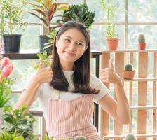 Porträt Garten Bauernhof Frau jung asiatisch Mädchen einer Person schön Lächeln genießen glücklich Stand Hand halten und suchen klein Grün Baum Topf Pflanzen Werkstatt Zimmer Haus und entspannen Sommer- Tag zum Job Hobby foto