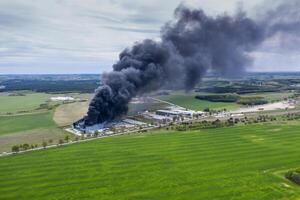 Antenne Aussicht von verbrannt industriell Warenhaus oder Logistik Center Gebäude nach groß Feuer mit enorm Rauch von verbrannt Dach foto