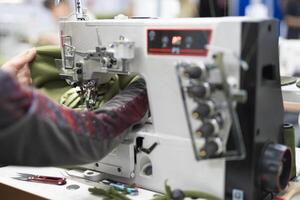 Arbeitskräfte im ein industriell Kleidungsstück Fabrik nähen Kleider auf Nähen Maschine foto