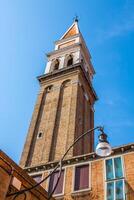 das farbig Häuser in der Nähe von das alt gelehnt Kirche Turm auf Burano Insel - - Venedig, Italien foto