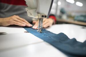 Arbeitskräfte im ein industriell Kleidungsstück Fabrik nähen Kleider auf Nähen Maschine foto