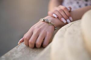 Nahansicht von ein Mädchen Hand mit ein schön Maniküre und ein Schmuck Armband auf ihr Hand foto