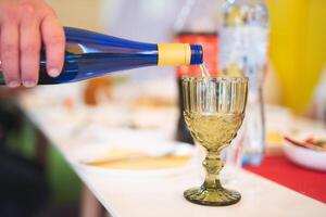 ein Bedienung im ein Restaurant gießt Alkohol in ein Glas beim das Tabelle foto