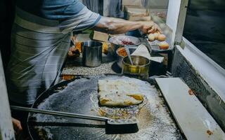 Herstellung Prozess von Martabak Telor. Bohnenkraut in der Pfanne fritiert Gebäck ausgestopft mit Ei, Fleisch und Gewürze. Martabak ist Beliebt nehmen Weg Essen unter malaysisch oder indonesisch. foto