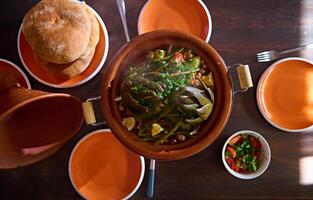 direkt über Foto zum Essen Blog von ein köstlich lecker Mahlzeit mit gedämpft Artischocken im marokkanisch Tajine Lehm Topf.