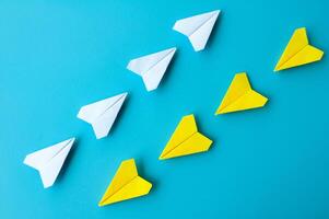 oben Aussicht von ein Weiß und Gelb Papier Flugzeuge Origami fliegend beim anders Richtung foto
