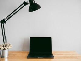 Laptop und einige stationäre Werkzeuge auf dem Schreibtisch aus Holz mit leerer grauer Wand als Hintergrund. Konzept des Arbeitsplatzes und des minimalen Büros. foto