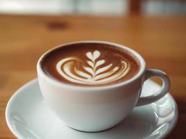 Tasse heißen Kaffee auf Holztisch im Café serviert.