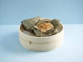 gedämpft klebrig Reis mit Hähnchen eingewickelt im Lotus Blatt serviert im ein hölzern Schüssel mit Essstäbchen isoliert auf Matte Seite Aussicht auf grau Marmor Hintergrund foto