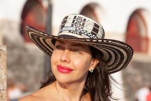 schön Frau tragen das traditionell kolumbianisch Hut namens Sombrero vueltiao beim das historisch calle de la Ronda von das Cartagena de Indien ummauert Stadt foto