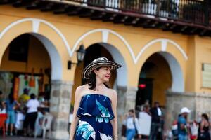schön Frau tragen das traditionell kolumbianisch Hut namens Sombrero vueltiao beim das Wagen Platz auf das historisch Straßen von Cartagena de Indien ummauert Stadt foto