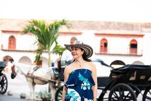 schön Frau tragen das traditionell kolumbianisch Hut namens Sombrero vueltiao beim das Zoll Platz auf das historisch Straßen von das Cartagena de Indien ummauert Stadt foto