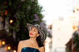 schön Frau tragen das traditionell kolumbianisch Hut namens Sombrero vueltiao beim das historisch Straßen von das Cartagena de Indien ummauert Stadt foto