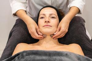 weiblich Kosmetikerin massieren Hals von Klient mit Steine foto