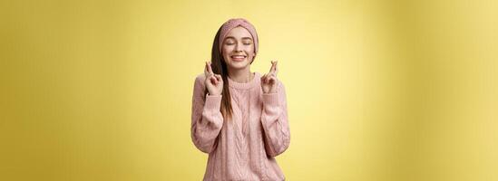 Mädchen wünsche Wellness wollen Traum Kommen Sie WAHR, Kreuz Finger verträumt, schließen Augen warten Wunder, vorwegnehmen gut Nachricht, posieren aufgeregt und froh gegen Gelb Hintergrund im gestrickt warm Sweatshirt foto