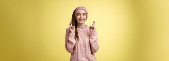 Kreuz meine Finger zum Du. unterstützend süß jung europäisch Freundin tragen Pullover, Glanz Stirnband Herstellung Glück, Wunsch Geste lächelnd hoffnungsvoll haben Vertrauen Traum Kommen Sie wahr Über Gelb Hintergrund foto