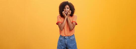 Frau Gefühl Empathie zum Freund habe im Ärger Stehen nervös Über Orange Hintergrund beißen Fingernägel runzelte die Stirn und Panik Sein erschrocken und schockiert Über Orange Hintergrund foto