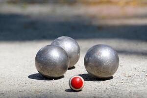 Petanque Bälle sind platziert in der Nähe von ein Ziel Ball auf ein draussen Schmutz Feld, wo 12 runden Metall Bälle sind geworfen wie schließen wie möglich zu das Ziel Mannschaft Das erreicht 13. das zuerst zu Ergebnis ist das Gewinner. foto