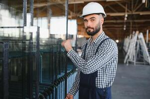 glücklich Fachmann schwer Industrie Ingenieur Arbeiter tragen Uniform, und schwer Hut im ein Stahl Fabrik. lächelnd industriell Spezialist Stehen im ein Metall Konstruktion Herstellung foto