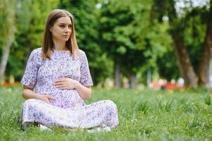 schöne schwangere Frau, die sich im Park entspannt foto