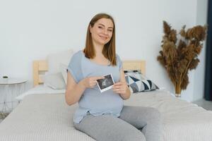 schwanger Frau halten Ultraschall Scan auf ihr Bauch foto