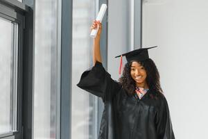 fröhliche afroamerikanische Doktorandin mit Diplom in der Hand foto