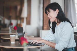 freiberuflich Konzept, ein Inhalt Frau ist konzentriert auf Tippen auf ihr Laptop beim ein Cafe Tisch, mit ein Kaffee Tasse und beiläufig Innere im das Hintergrund. foto