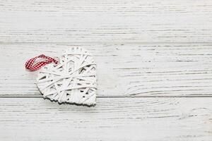 dekorativ Weiß Ranke Herz, Spielzeug zum Dekoration auf ein hölzern Hintergrund. foto