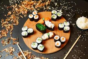 hölzern Teller mit Sushi und Essstäbchen foto