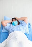 Fett asiatisch Frau im Krankenhaus tragen Maske sie war Lügen im Bett mit ein sehr Kopfschmerzen. Konzept von medizinisch Dienstleistungen im Krankenhäuser. Gesundheit Versicherung foto