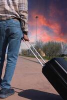 ein Mann ist ziehen ein Koffer mit ein handhaben. Urlaub Verschwörung. Sommer- Zeit foto