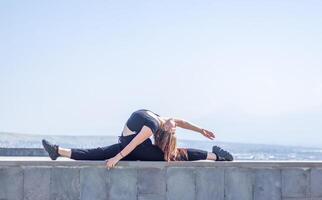 jung Mädchen tun Übung im das Stadt, Frau tun Yoga Übung, Person tun dehnen, Frau entspannend im das Stadt, ziemlich Mädchen tun Fitness Übung foto