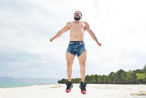 jung muskulös Mann ausüben auf das Strand, jung muskulös Mann tun Körperbau Übungen auf das Strand, sportlich jung Mann auf das Strand foto