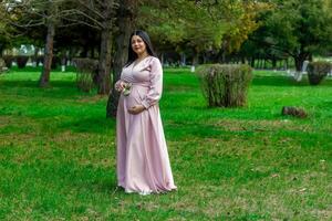 das schwanger Frau im das Park, schön Frau im das Park, schwanger Frau im Frühling foto