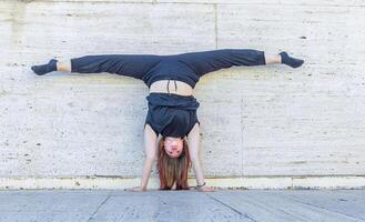 jung Mädchen tun Übung im das Stadt, Frau tun Yoga Übung, Person tun dehnen, Frau entspannend im das Stadt, ziemlich Mädchen tun Fitness Übung foto