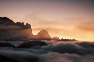 atemberaubender Sonnenuntergang unter den Felsen, die mit hartem Nebel gefüllt sind foto