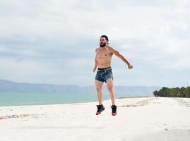 jung muskulös Mann ausüben auf das Strand, jung muskulös Mann tun Körperbau Übungen auf das Strand, sportlich jung Mann auf das Strand foto