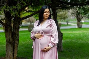 das schwanger Frau im das Park, schön Frau im das Park, schwanger Frau im Frühling foto