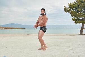 jung muskulös Mann ausüben auf das Strand, jung muskulös Mann tun Körperbau Übungen auf das Strand, sportlich jung Mann auf das Strand foto